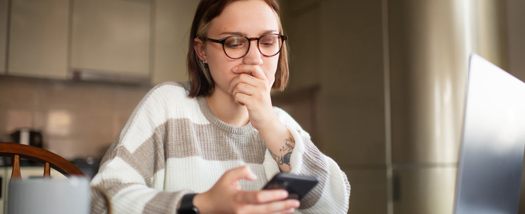 Mulher desconfiada a olhar para o telemóvel